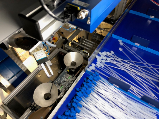 A robot sorts catheters with blue and white attachments using an Ensenso 3D camera.