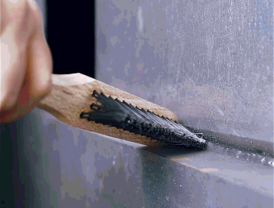 Hand that cleans weld seams or metal surfaces with a wire brush