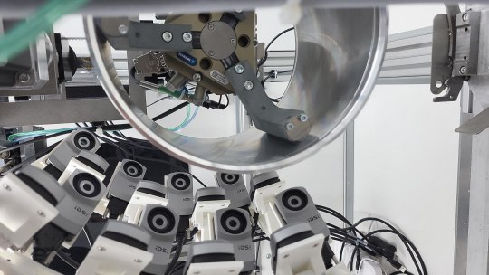 More than a dozen IDS uEye XC cameras capture the outer surface of a round aluminium component.