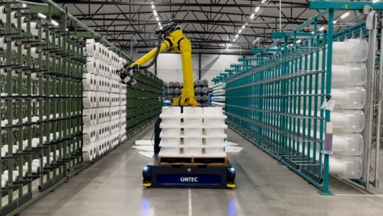 Pick-and-place robot in a logistics hall with paper rolls