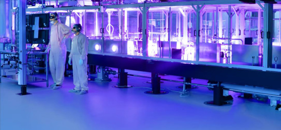 Two employees in protective clothing inside a research laser
