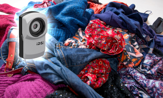 uEye XC camera in front of a mountain of old clothes