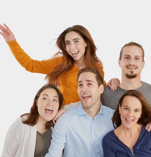 Two men and three women stand joyfully together as a group in front of a white background.