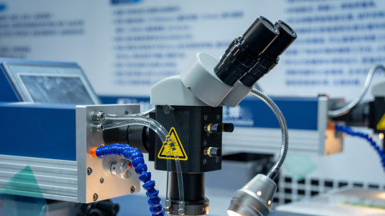 Binocular microscope with tubing and a lamp in a laboratory set-up.
