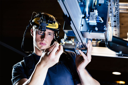 A man with a helmet camera carries out assembly work on a machine