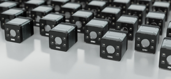 Industrial cameras in cube form lie in rows on a reflective surface.