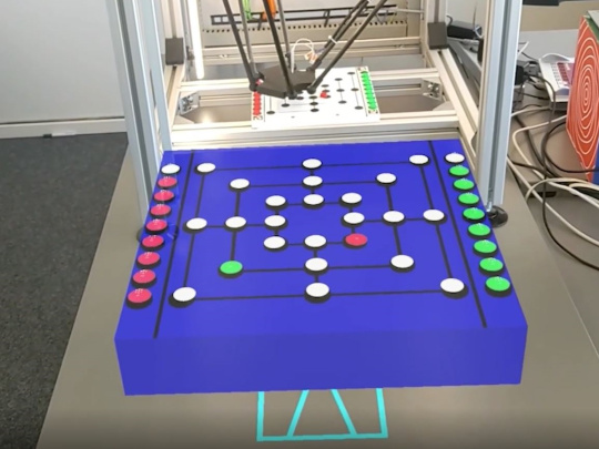 Robot plays mill in box, in front of box the equivalent game board to play against the robot